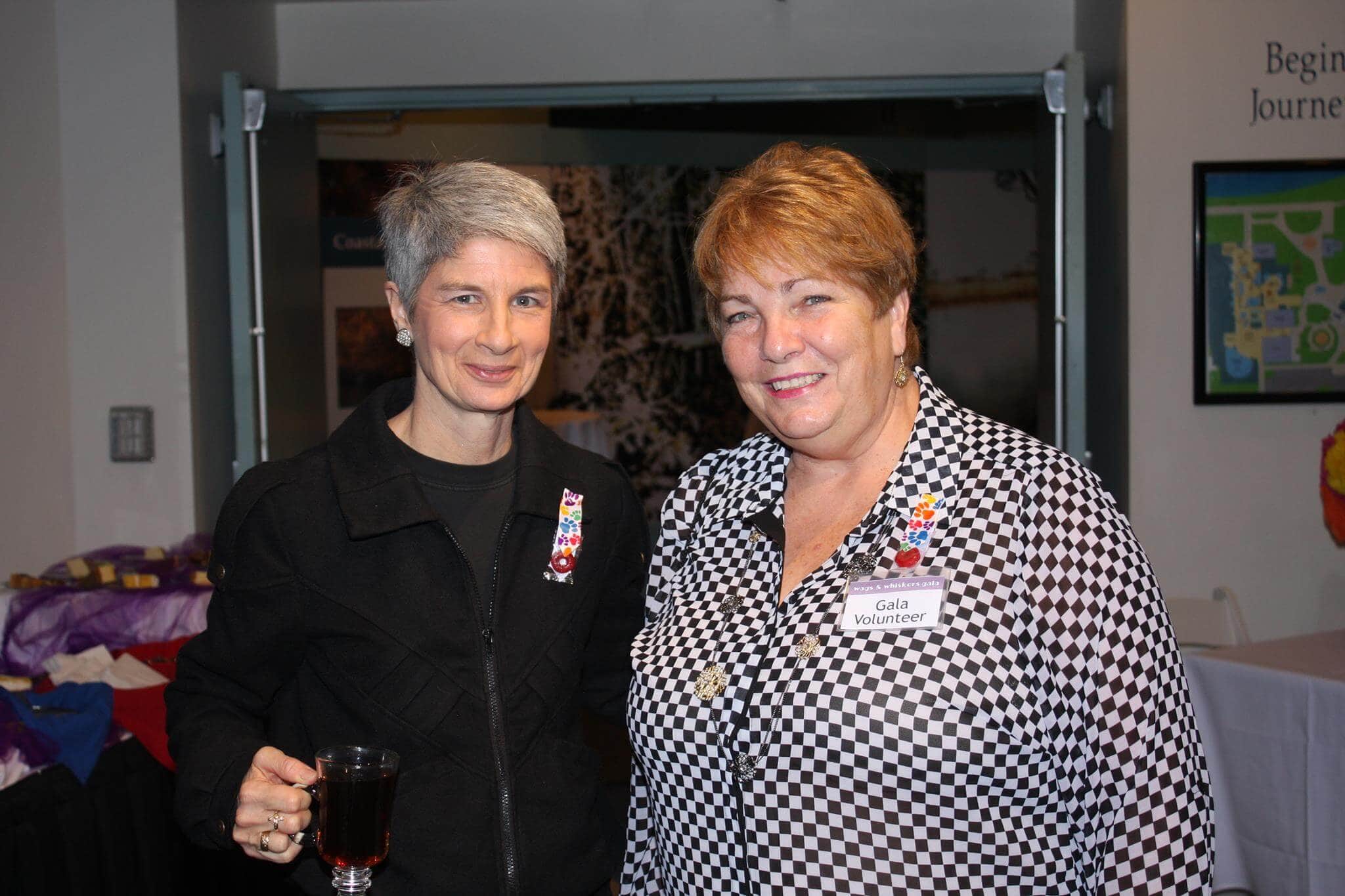 Kim Kalman at a social event with a volunteer, smiling and holding a drink.