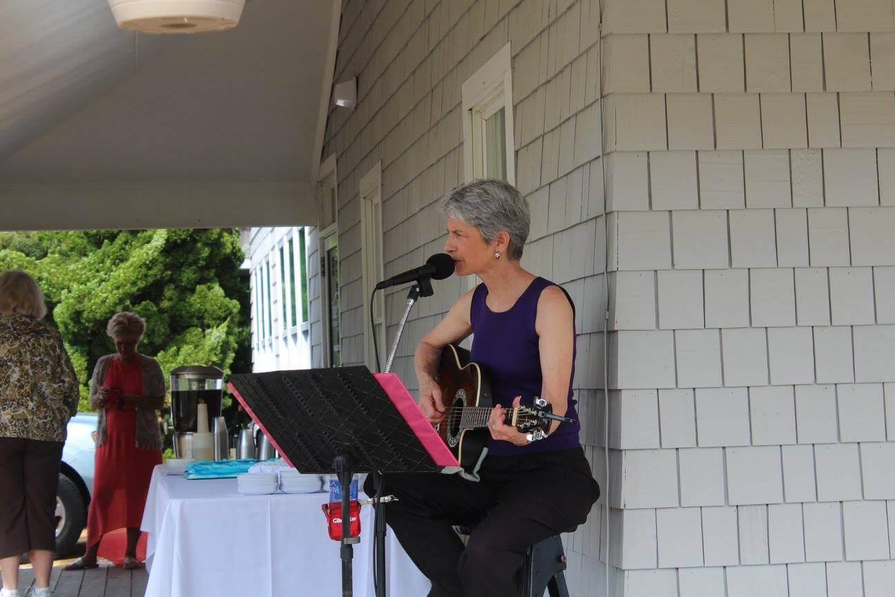 Performing singer-songwriter Kim Kalman plays guitar at an outdoor event.